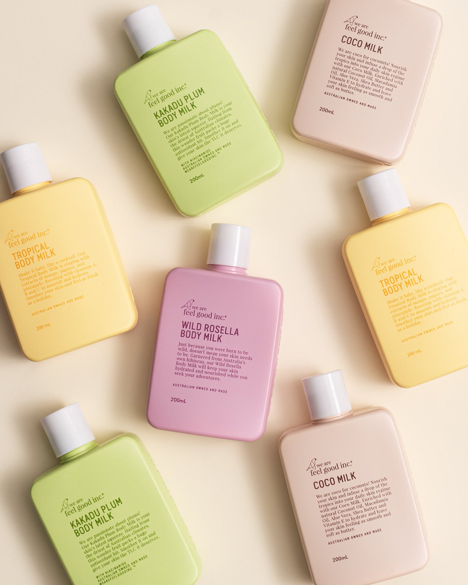 An array of We Are Feel Good Inc. body milk lotions in pink, peach, and beige, with a lime green one in a netted tote bag
